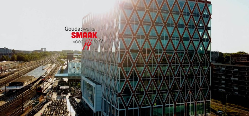 Dronefoto van het Huis van de Stad. Links daarvan het logo Gouda: welke smaak voeg jij toe?